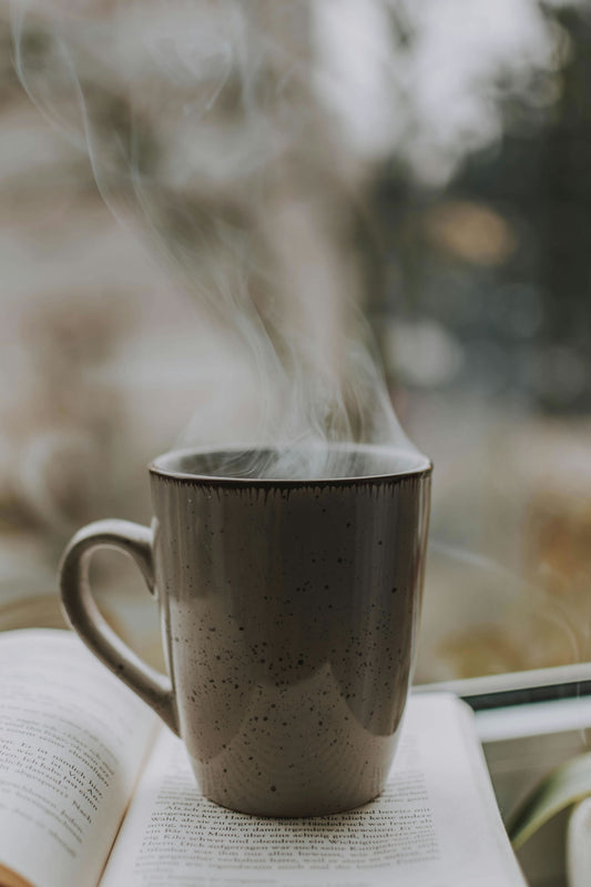 Cup of hot coffee on top of a book