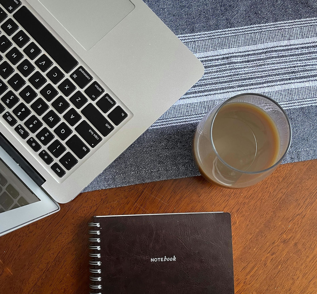 Cup of coffee with laptop and notebook on the table.