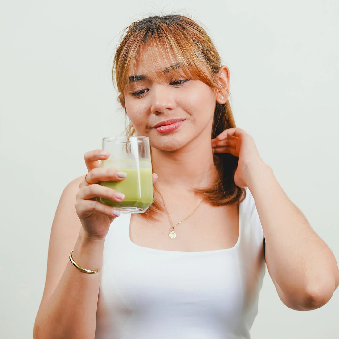 Woman holding a cup of green matcha and looking at it.